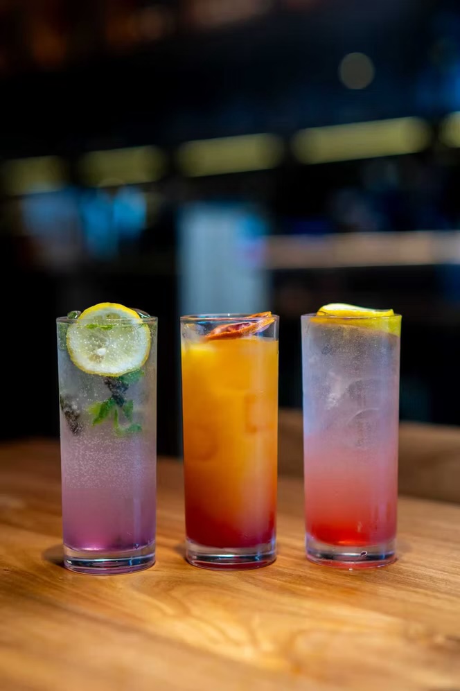 Three colorful cocktails lined up on the bar