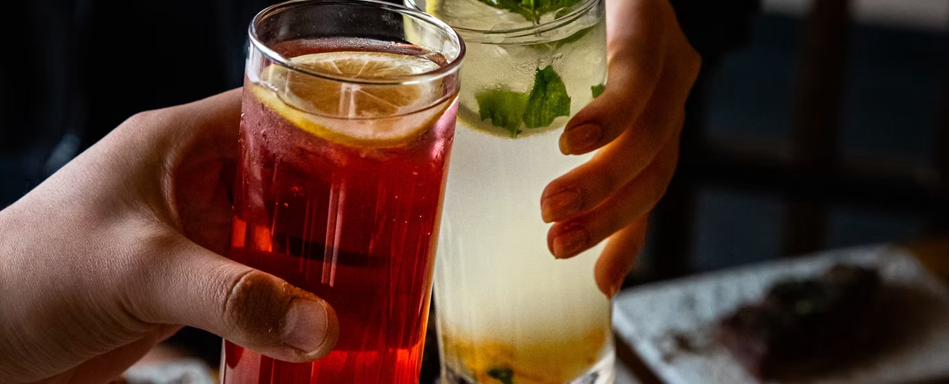 Friends toasting with fruit tea and a mint cocktail