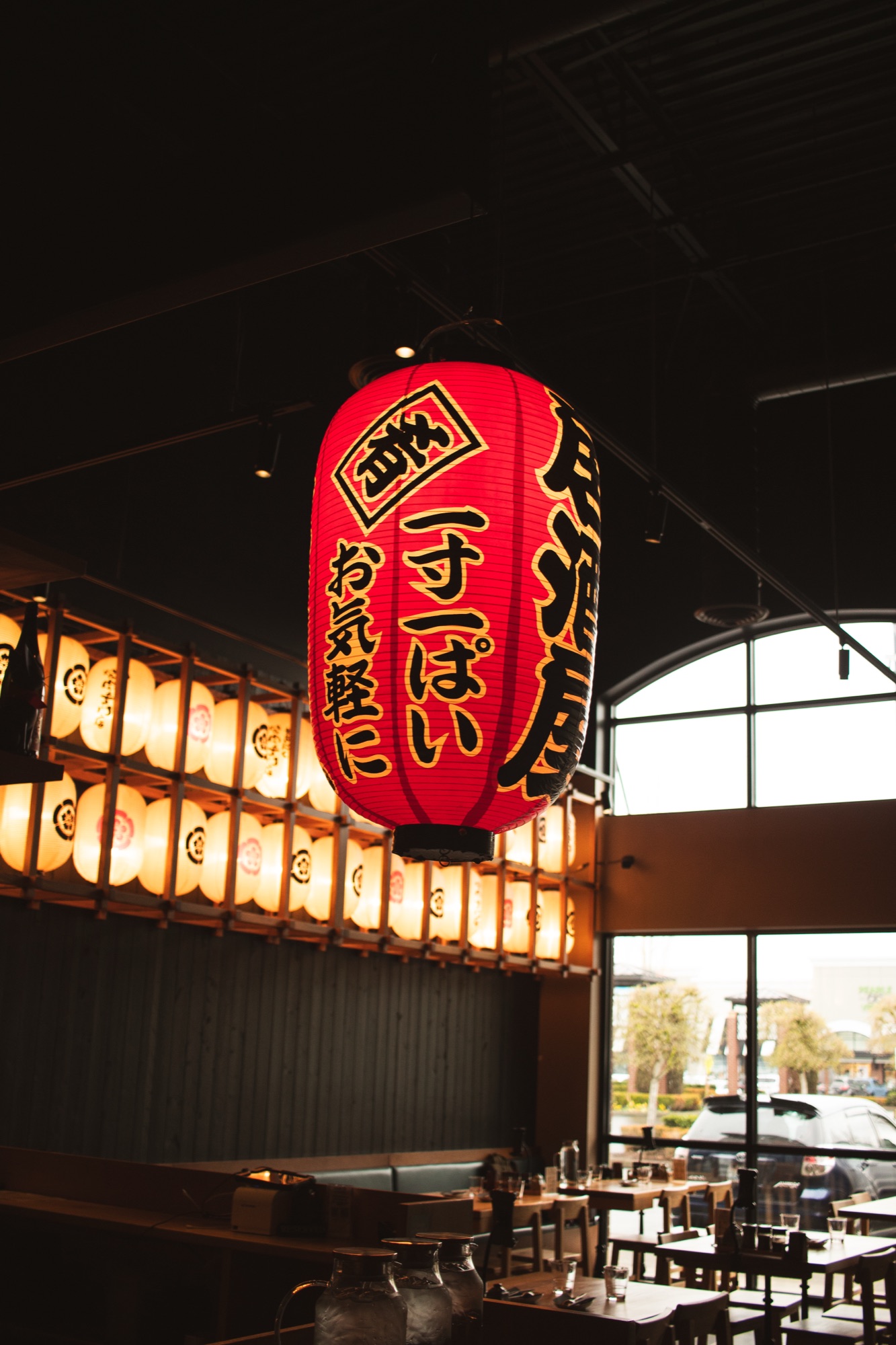Giant red chochin lantern glowing above the dining room, wall of lit lanterns behind