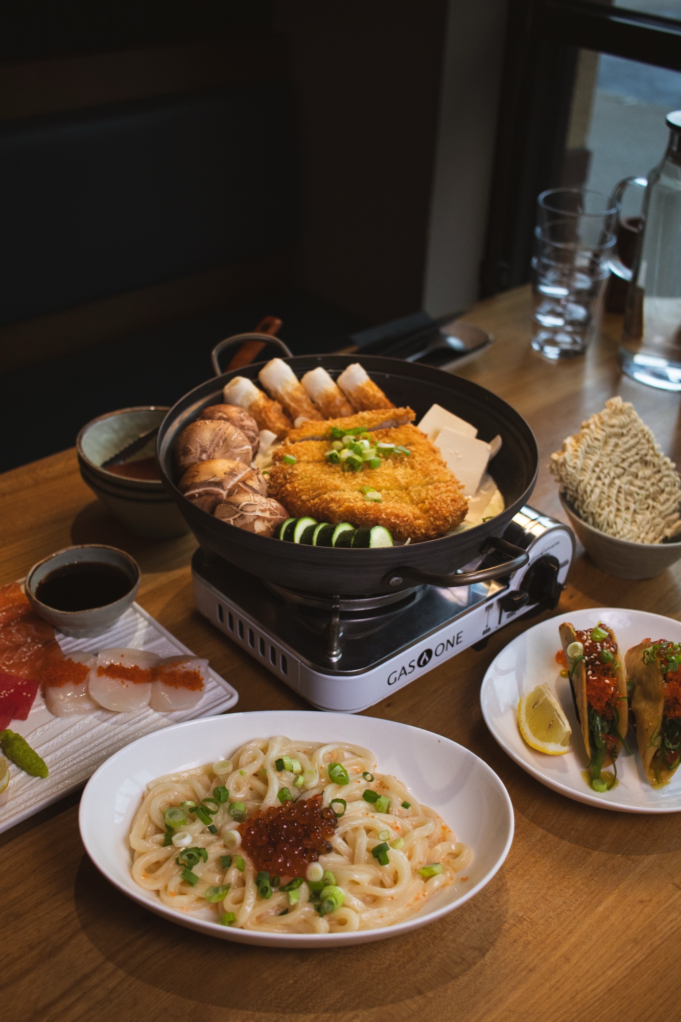 Table spread of hotpot, udon, sushi and izakaya small plates